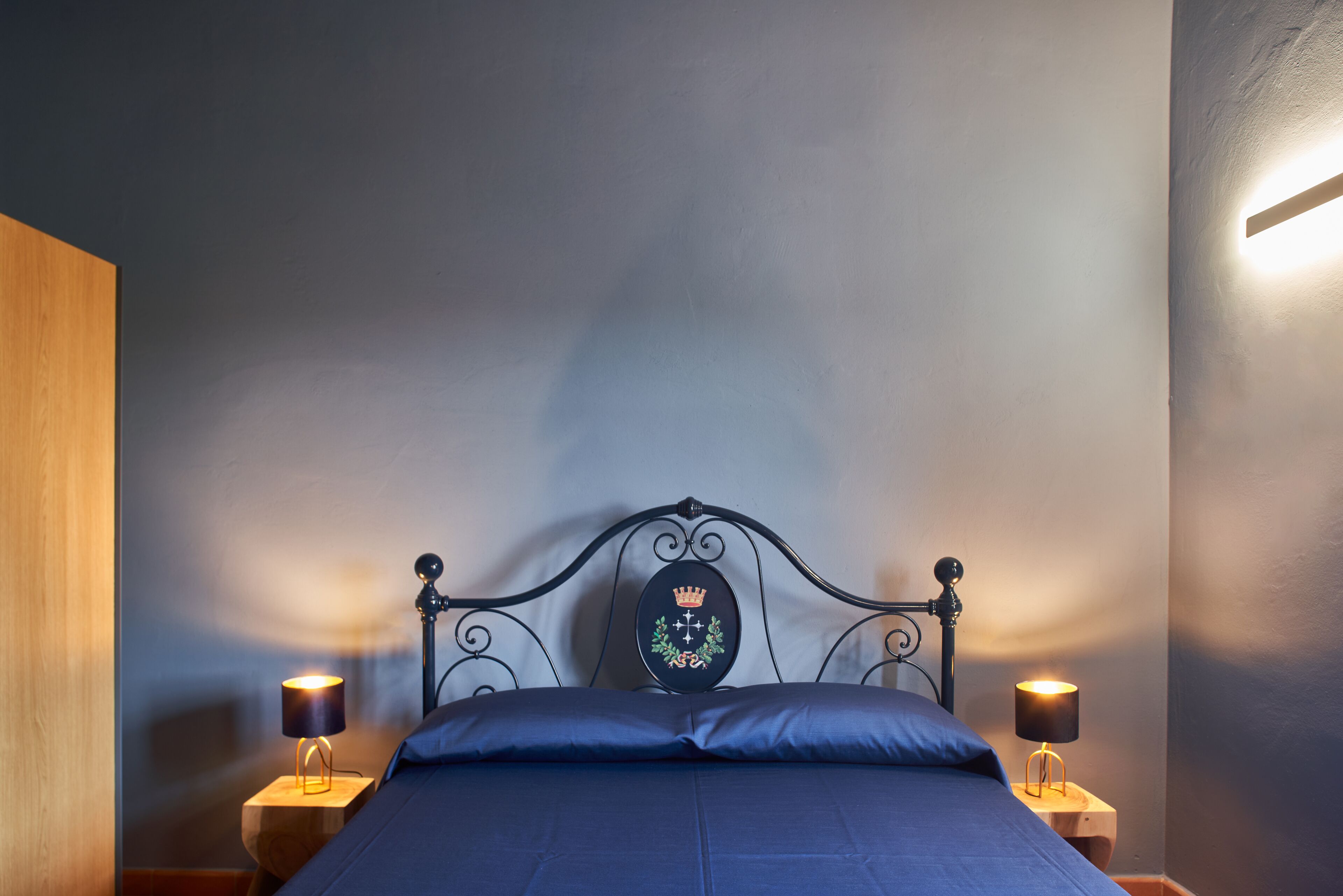 A bedroom with a bed, two bedside tables with lamps, and a decorative headboard.
