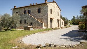 A stone building with a gravel driveway and a clear sky. - Podere Sant'Antonio (Asciano)