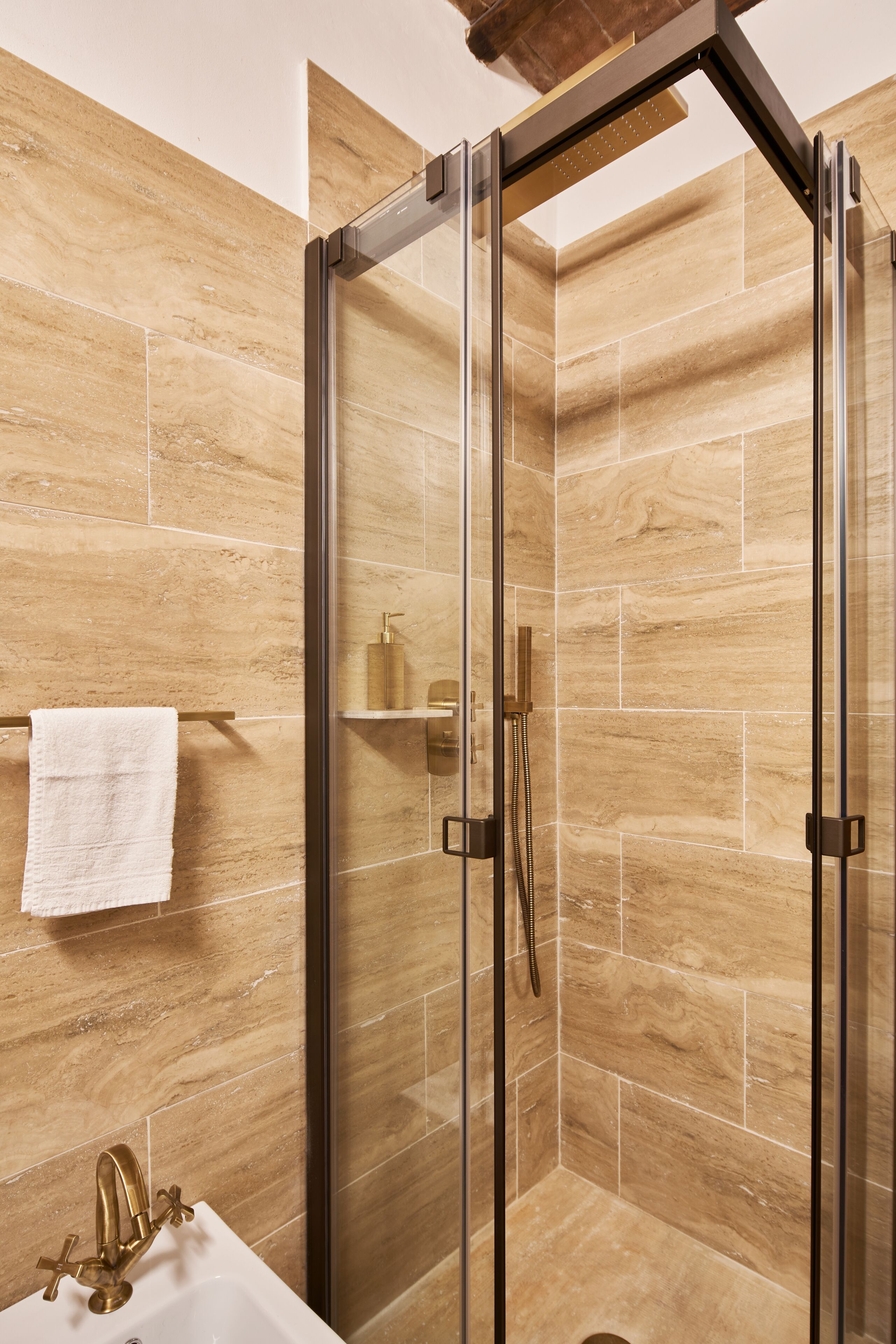 A modern bathroom with a glass-enclosed shower, a white sink, and a towel rack.