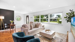 A modern living room with a sofa, two armchairs, a coffee table, and a painting on the wall. - 4 BR, 5 Bed, 2 King, 2 Bath, Private Pool (Cocoa Beach)