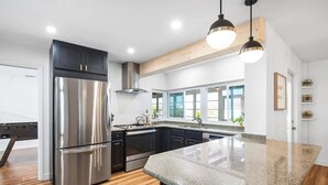 A modern kitchen with stainless steel appliances, a granite countertop, and a wooden ceiling beam. - 4 BR, 5 Bed, 2 King, 2 Bath, Private Pool (Cocoa Beach)