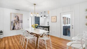 A dining area with a wooden table, white chairs, and a chandelier. - 4 BR, 5 Bed, 2 King, 2 Bath, Private Pool (Cocoa Beach)