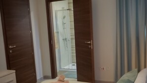 Un dormitorio con cama, armario, zona de ducha y lámpara colgante.