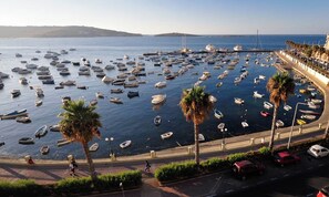 A marina with numerous boats docked, a promenade with palm trees, and a clear view of the sea. - Spacious 3BR Apt Central Located With Sea Views (St. Paul's Bay)
