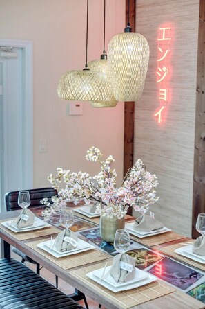 Une table à manger dressée avec des sets de table, des serviettes pliées et un vase de fleurs.
