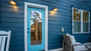 A house with a blue exterior, a white door, and two windows with lights.