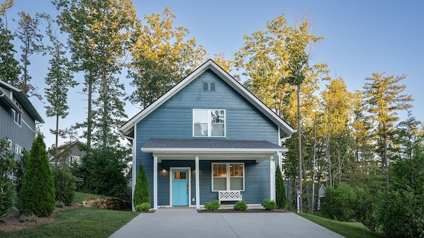 A two-story house with a blue exterior, a front porch, and a small front yard.