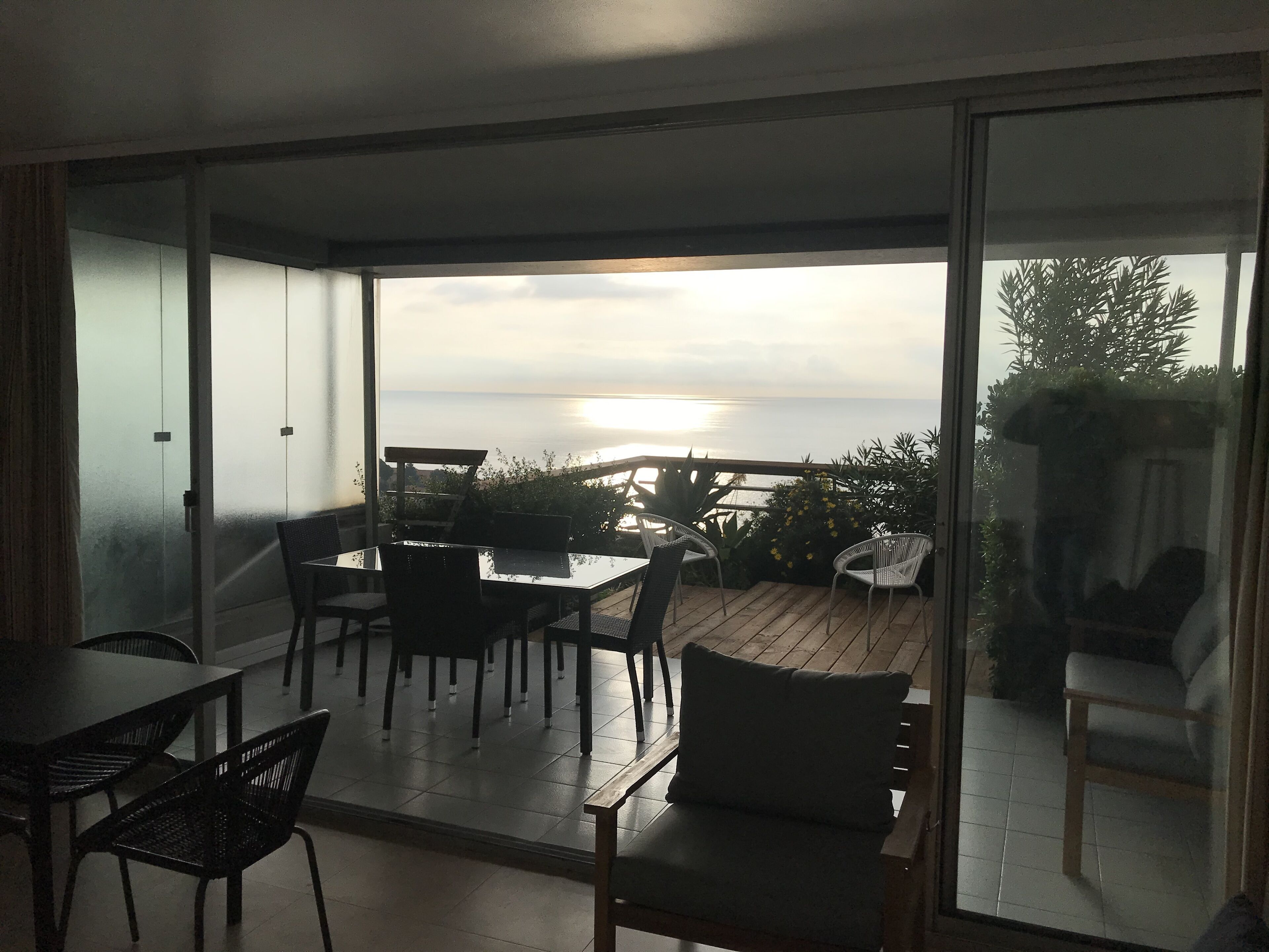 Een balkon met een tafel en stoelen, met uitzicht op een wateroppervlak.