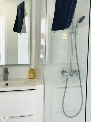 A modern bathroom with a glass-enclosed shower, a white sink, and a mirror. - Costa Plana Collection (Cap d'Ail)