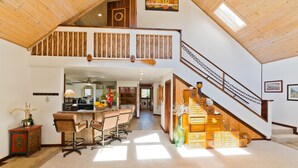 Un loft spacieux avec de hauts plafonds, un coin cuisine, un espace repas avec des tabourets de bar et un escalier menant à un niveau supérieur.
