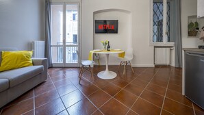 A modern living room with a grey sofa, a small round table, and a TV mounted on the wall. - [Ghirlandina] Fantastic loft in the city center (Modena)