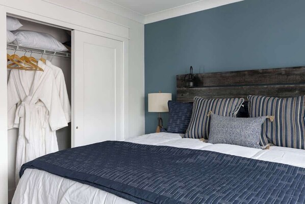 A bedroom with a bed, a wardrobe, and a nightstand with a lamp.