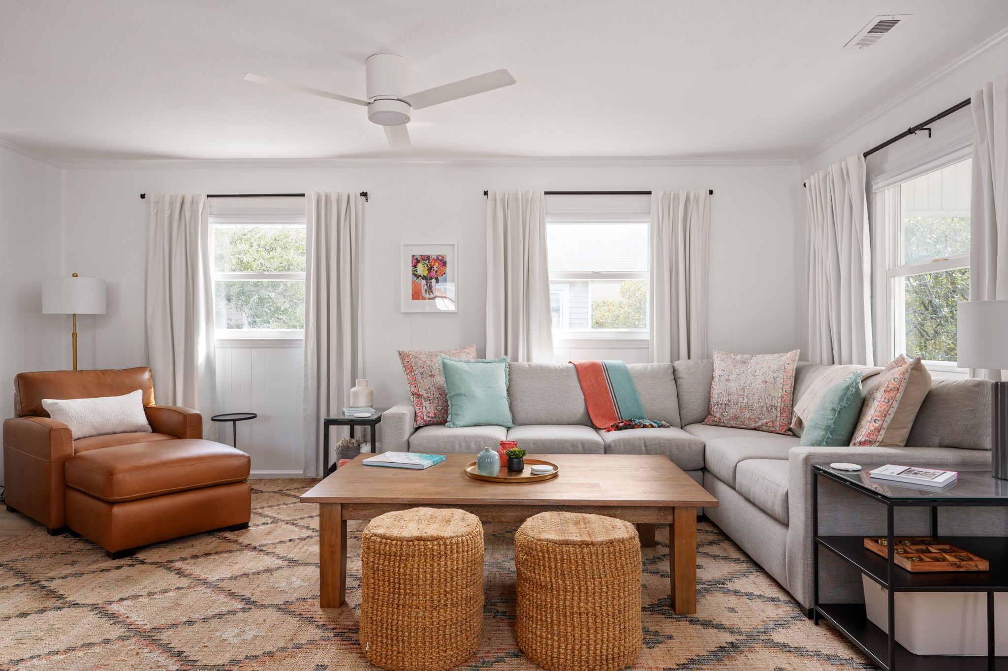 A living room with a sofa, armchair, coffee table, and two ottomans.