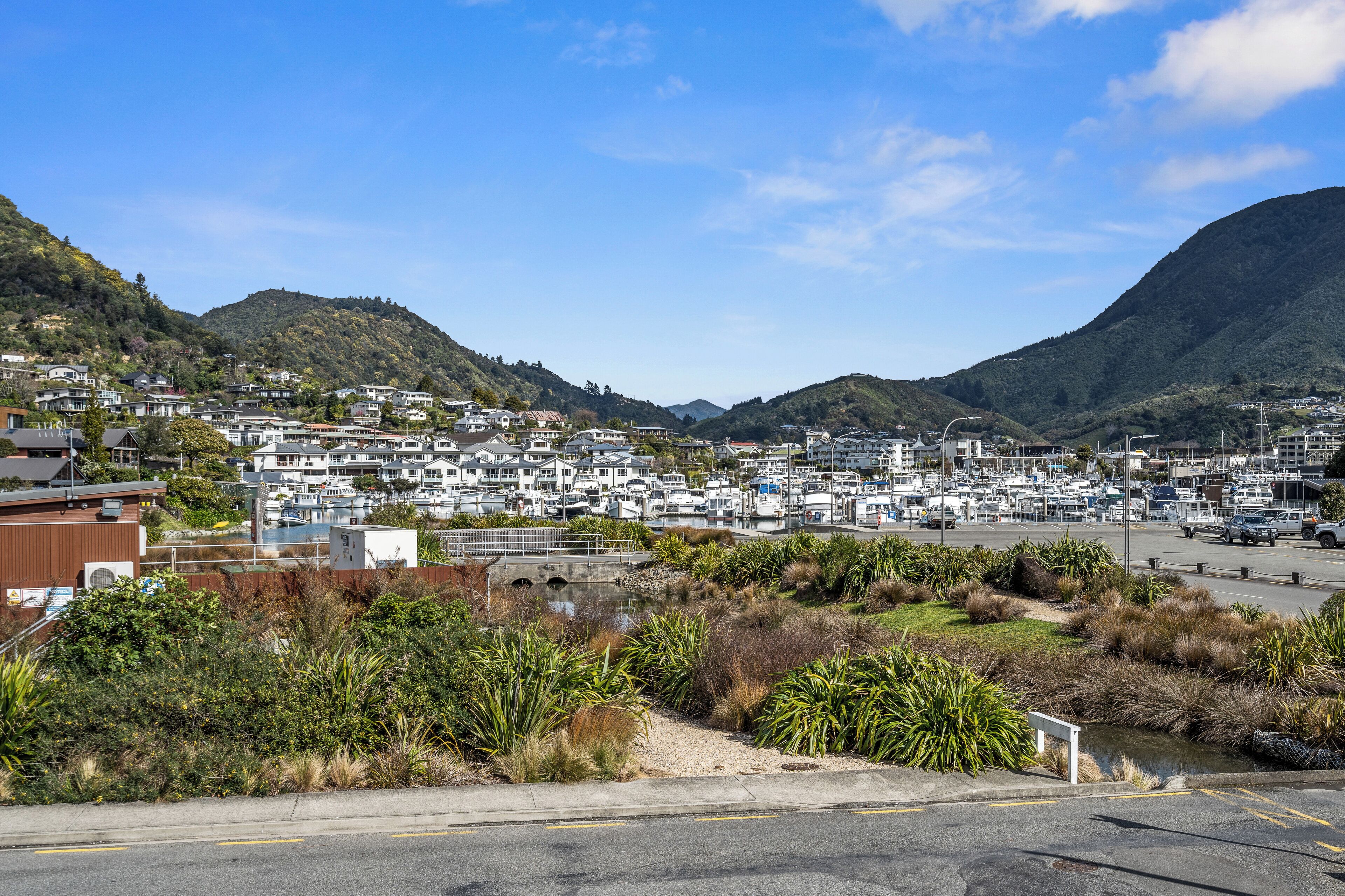 A marina with boats, a small bridge, and a hillside residential area.