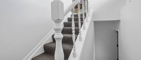 A staircase with white balusters and a carpeted landing.