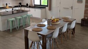 A modern kitchen with a central island, bar stools, and a dining table set for six.