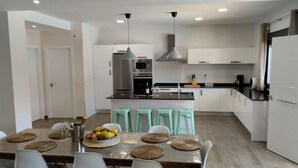 A modern kitchen with white cabinets, stainless steel appliances, and a central island with stools.