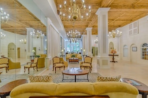 A spacious lobby with high ceilings, chandeliers, and a central seating area. - Pineapple Pad 2.0 | Sleek 1BR · Steps to the Beach (Palm Beach)