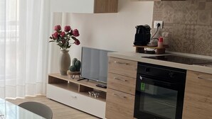 A modern kitchen with wooden cabinets, a built-in oven, a glass dining table, and a vase with flowers. - Loft Crispi Refined, cozy and functional apartment. (Siracusa)