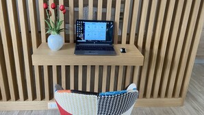 A laptop on a wooden shelf with a potted plant and red flowers. - Loft Crispi Refined, cozy and functional apartment. (Siracusa)