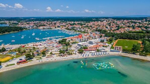 Oversigtsbillede af en kystby med lystbådehavn, strand og boligbebyggelse.