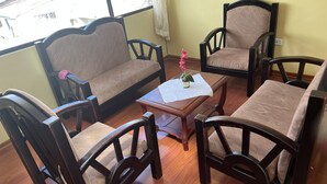 Quarto com sofá, duas poltronas e uma mesinha com planta em vaso.