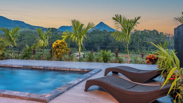A pool area with lounge chairs and a view of mountains. - Kaluma Frog Farmstay Villa La Fortuna (San Ramon)