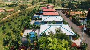 A resort with multiple buildings, a swimming pool, and lush greenery. - Kaluma Frog Farmstay Villa La Fortuna (San Ramon)