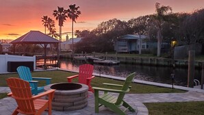 A waterfront patio with Adirondack chairs, a fire pit, and a gazebo. - St Augustine waterfront home on canal w/ private dock, walk to beach! (St. Augustine)