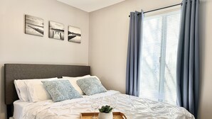 A neatly made bed with a wooden tray, a potted plant, and a wine glass. - Fast Wi-Fi/Comfy beds/Free parking/3bdr house/4TVs
 (Aurora)