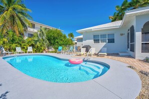 A swimming pool with lounge chairs and a palm tree in the background.