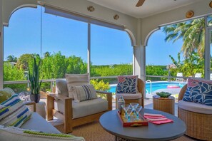 A sunlit room with large windows, a pool, and outdoor seating. - P40 - Premier 3 bedroom, 2 bathroom home with private pool and dockage. (Marathon)