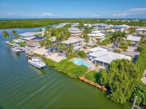 A coastal residential area with houses, a swimming pool, and a dock with a boat. - P40 - Premier 3 bedroom, 2 bathroom home with private pool and dockage. (Marathon)