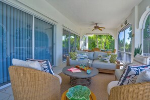A spacious balcony with wicker furniture, a ceiling fan, and large windows offering a view of greenery. - P40 - Premier 3 bedroom, 2 bathroom home with private pool and dockage. (Marathon)
