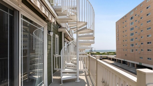 A balcony with a spiral staircase, a view of the sea, and a building with the number 1900 on it. - Great Beach Condo Right Near the Boardwalk Awesome Rooftop Views of the Ocean (Wildwood)