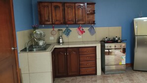 A kitchen with wooden cabinets, a stove, a refrigerator, and a sink. - TOTY SUITE: Very quiet and familiar, with a panoramic view of the entire city (Quito)