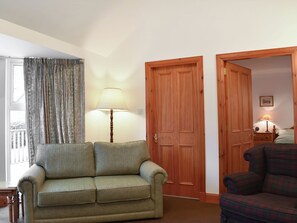 A living room with a sofa, a lamp, and a door leading to another room.