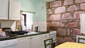 Een keuken met witte kasten, een wasmachine, een fornuis en een tafel met een gele tafelkleed.