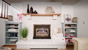 A living room with a white brick fireplace, wooden shelves, and a staircase. - Home Calls the Heart- 10 minutes to Mayo.  Split-level home with fenced-in yard. (Rochester)