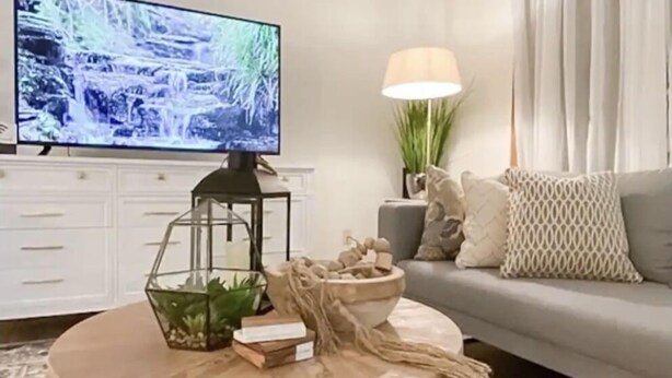 A living room with a round coffee table, a flat-screen TV, a sofa, and a lamp. - Home Calls the Heart- 10 minutes to Mayo.  Split-level home with fenced-in yard. (Rochester)