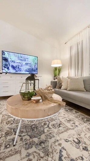 A living room with a round coffee table, a flat-screen TV, a sofa, and a lamp. - Home Calls the Heart- 10 minutes to Mayo.  Split-level home with fenced-in yard. (Rochester)