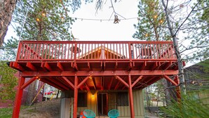 A wooden deck with a red railing, two turquoise chairs, and a small porch area. - Cozy Mountain Getaway in Arrowbear Lake, minutes from ski resorts. Pet-Friendly! (Running Springs)