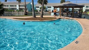 A swimming pool with clear blue water, surrounded by palm trees and a fenced area. - Waterfront Getaway with private boat slip on desirable Key Allegro, Rockport Tx (Rockport)
