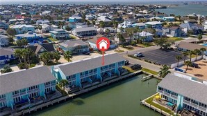A coastal residential area with a prominent blue building featuring a dock and a parking lot. - Waterfront Getaway with private boat slip on desirable Key Allegro, Rockport Tx (Rockport)