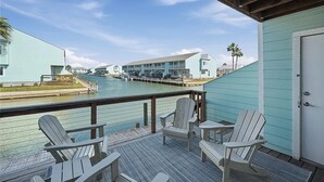 A waterfront property with a deck, chairs, and a view of a dock and buildings. - Waterfront Getaway with private boat slip on desirable Key Allegro, Rockport Tx (Rockport)