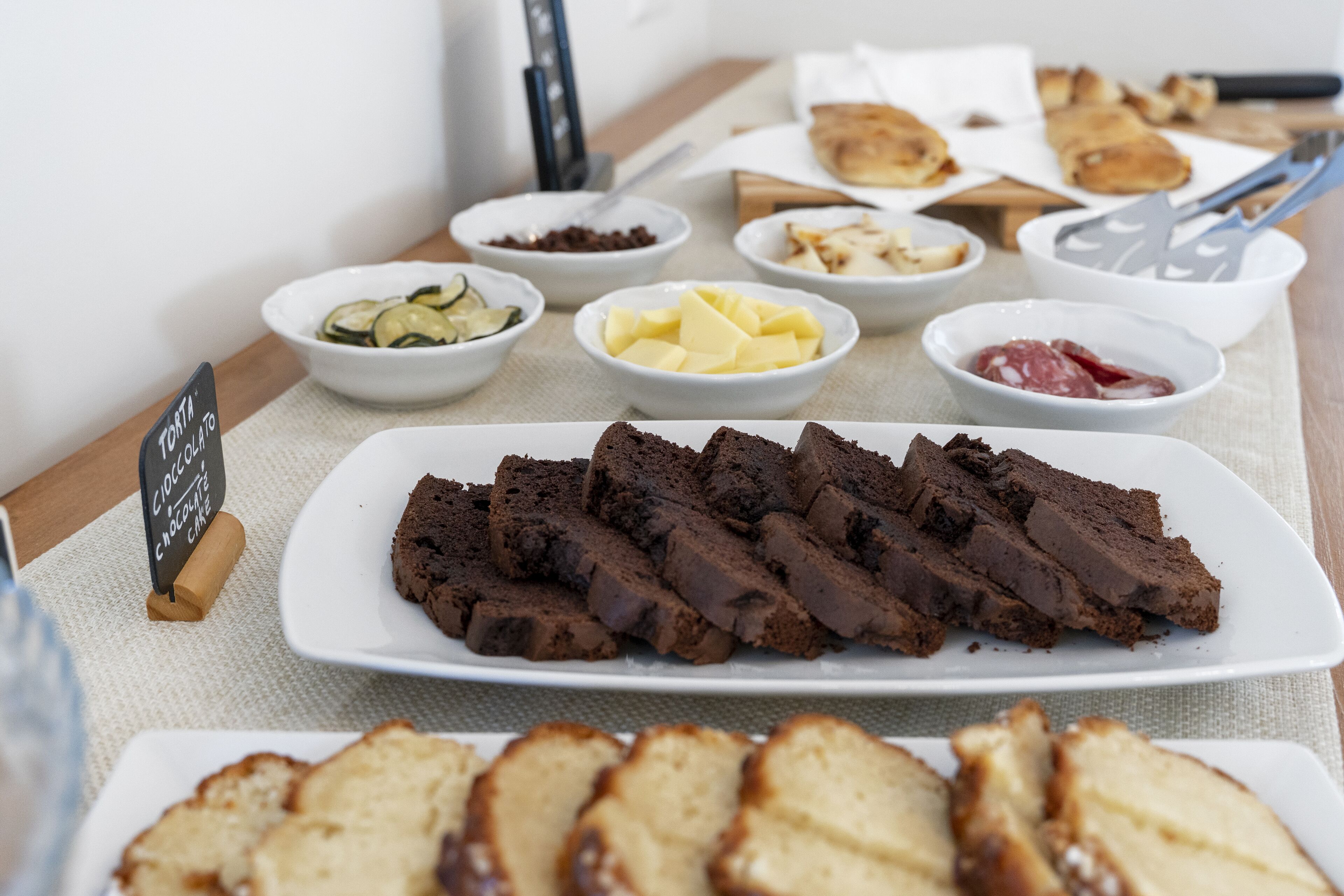 A table with various food items including chocolate brownies, cheese, and bread.