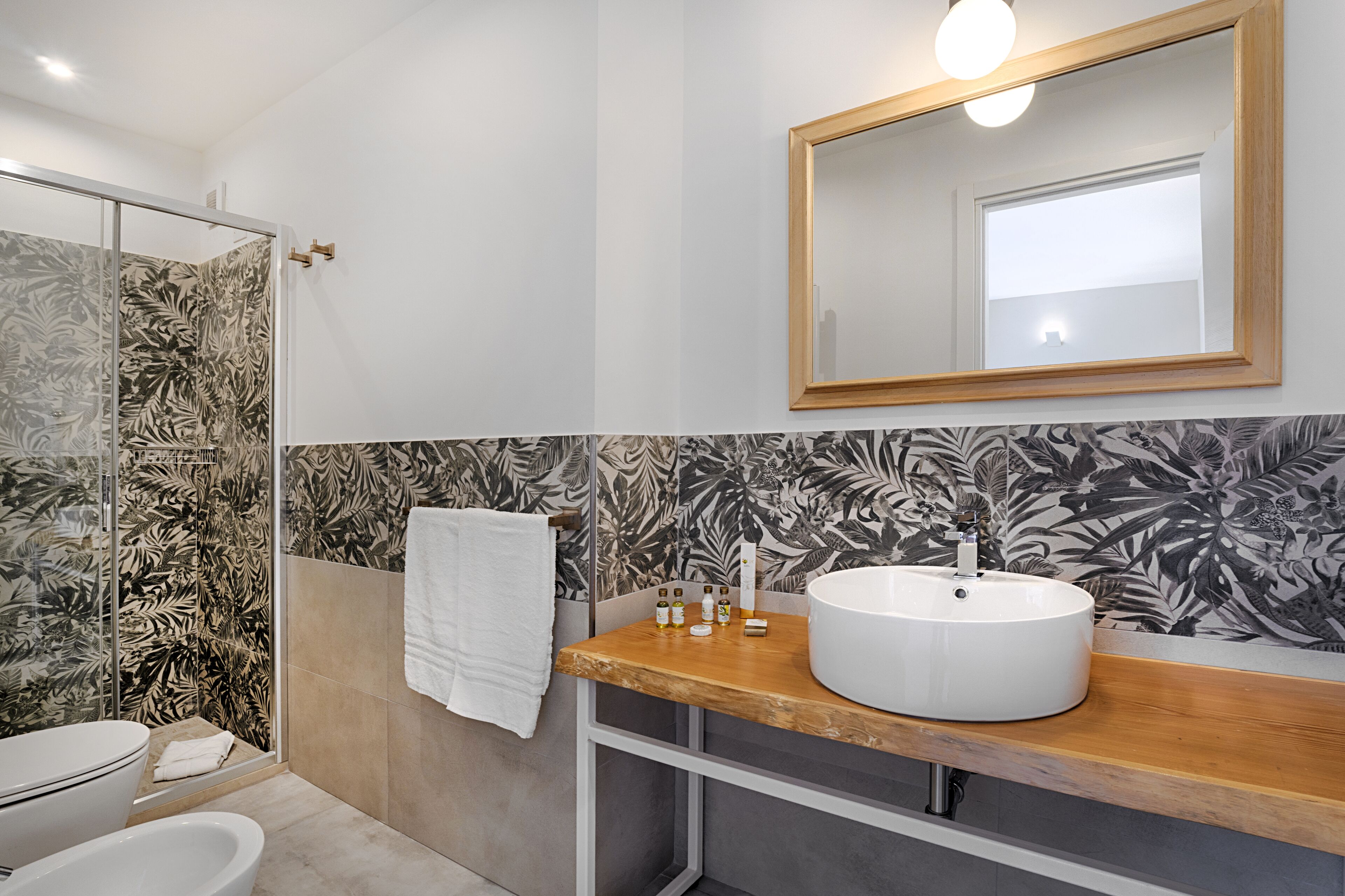 A bathroom with a glass shower, a white sink, and a mirror above it.