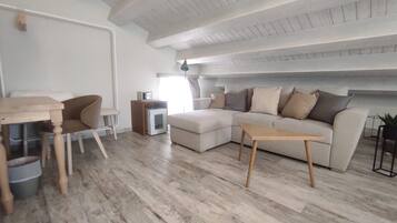 Ein modernes Wohnzimmer mit Holzboden, einer Couch, einem Couchtisch, einem kleinen Tisch und einer TV-Konsole.