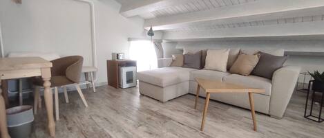 Una sala de estar moderna con piso de madera, un sofá, una mesa de centro, una mesita auxiliar y un mueble para televisor.