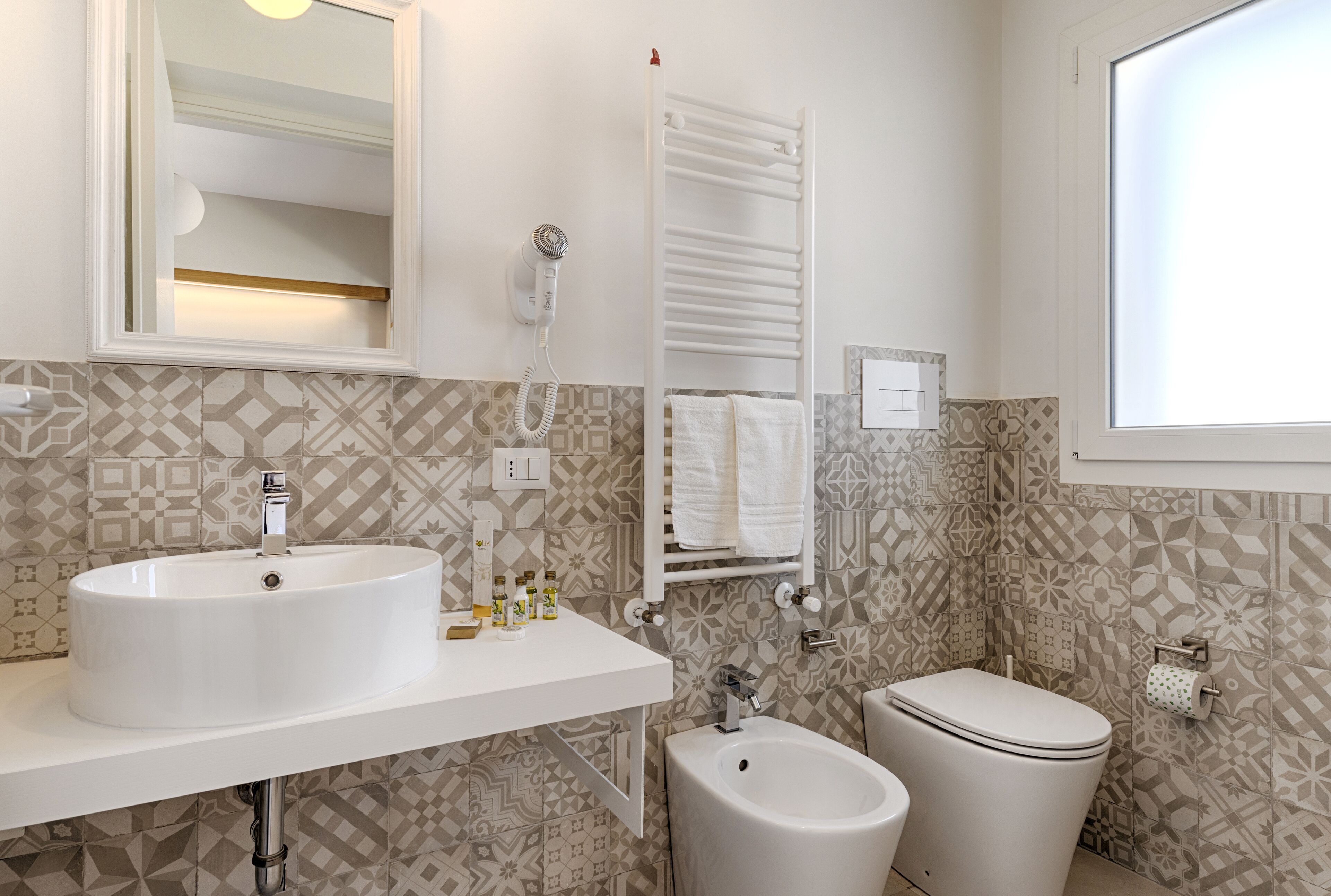 Un baño con un lavabo blanco, un bidé, un inodoro y un perchero para toallas.